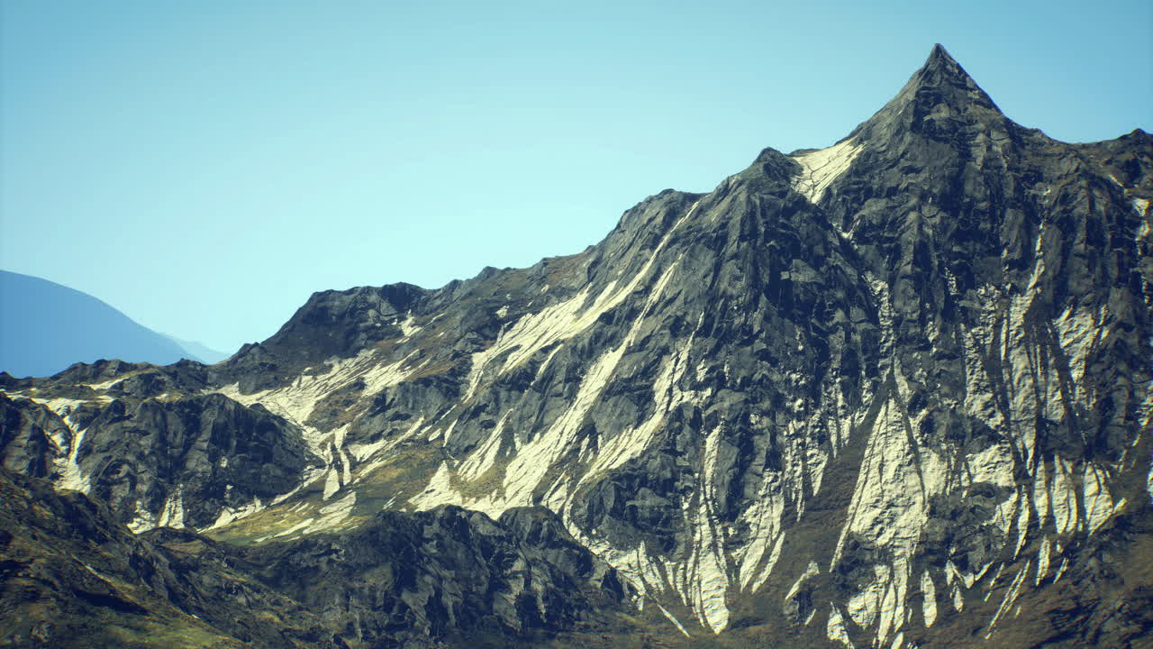 Puncak gunung megah menjulang di bawah langit biru cerah di lokasi terpencil.