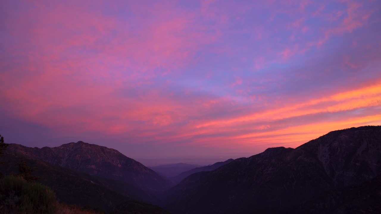 Il sole sta tramontando sulle montagne con cielo viola e nuvole