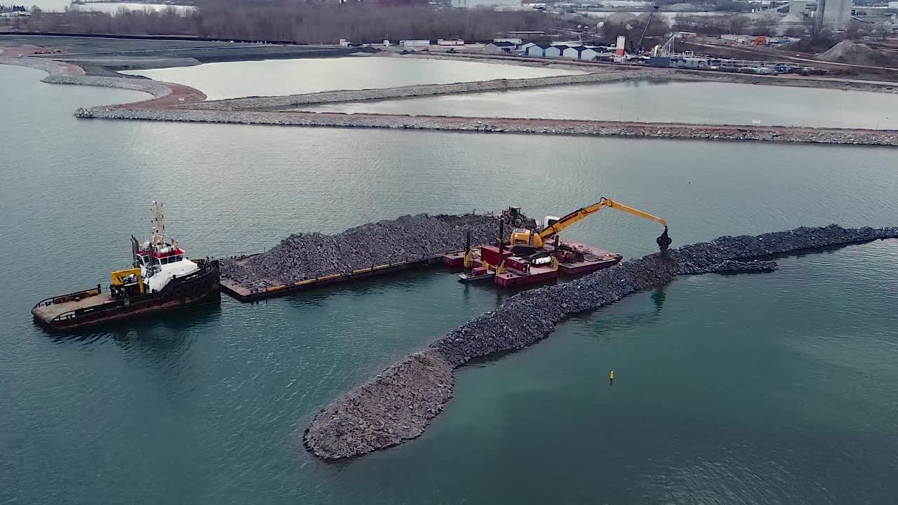 해안가 항구 근처의 암석에서 바지선 건물 방파제에 있는 굴삭기