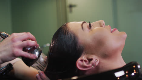 Female-hairdresser-washing-hair-of-female-customer-at-hair-salon