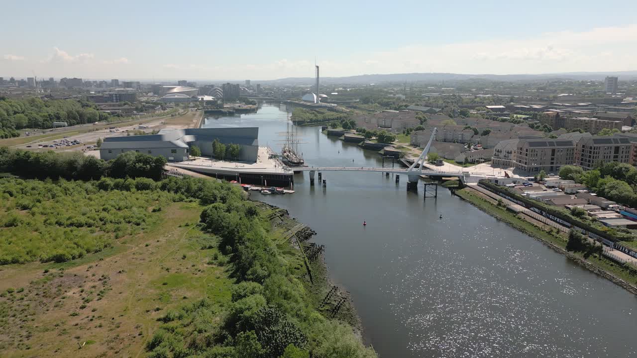 Aerial side on pullback of Riverside Museum and Swivelly Bridge with Glasgow skyline in background, Glasgow, Scotland, UK