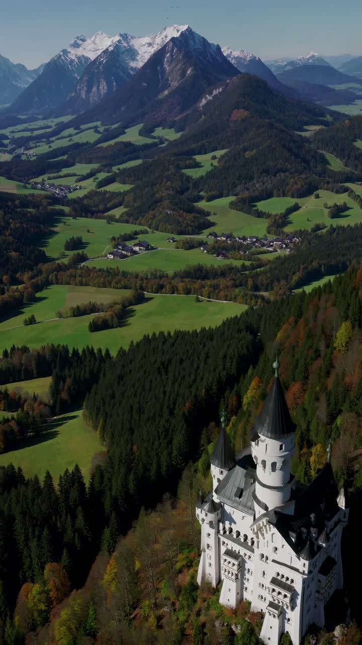 Ripresa video aerea di un castello da favola circondato da foreste lussureggianti e montagne maestose