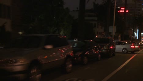 un automóvil viaja a lo largo de una calle en la noche en los ángeles california como se ve a través de la ventana trasera en un ángulo 4