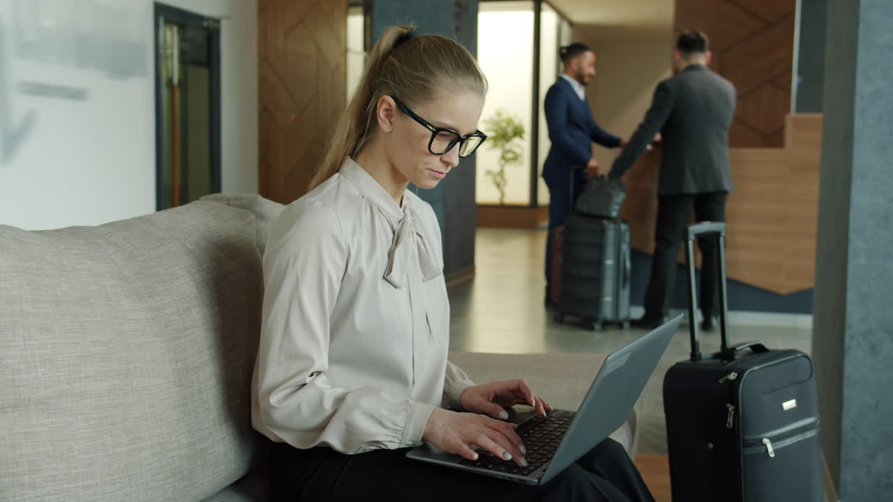 Businesswoman working on laptop in hotel lobby