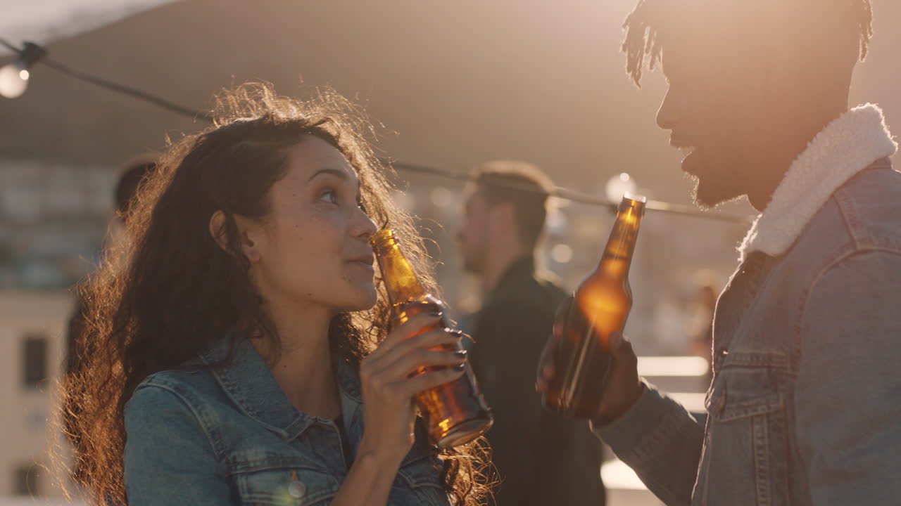 grupo de amigos pasando el rato juntos disfrutando de una fiesta en la azotea al atardecer tomando selfies usando teléfonos inteligentes bebiendo alcohol divirtiéndose el fin de semana compartiendo celebraciones