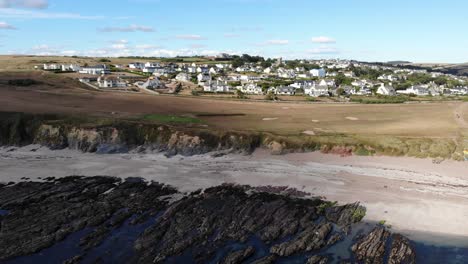 aerial view of empty beach with striation rocks at low tide with thurlestone village in background