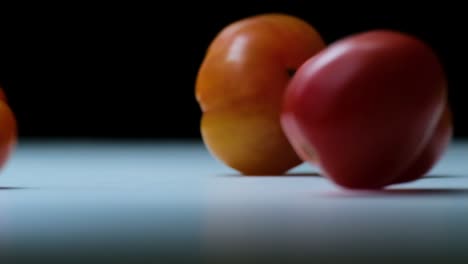cinematic slow motion shots of heirloom tomatoes being tossed on a work surface, clean, sharp, dark background