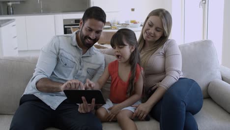 padres felices y hija linda sentada en el sofá
