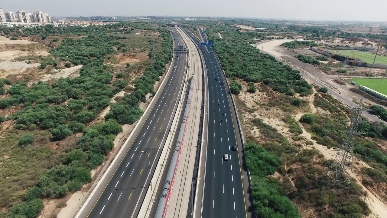 기차는 도시를 향해 고속도로 근처를 여행합니다.