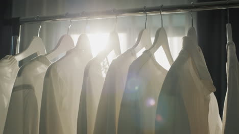 white clothes hang on hangers, the sun shines beautifully on it.