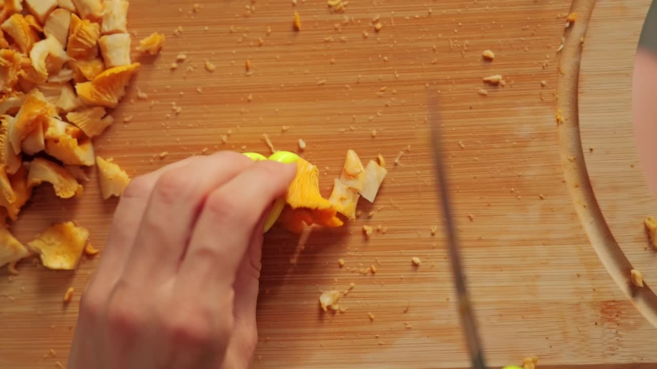Macro top down view of chanterelles being chopped into small pieces, wood board