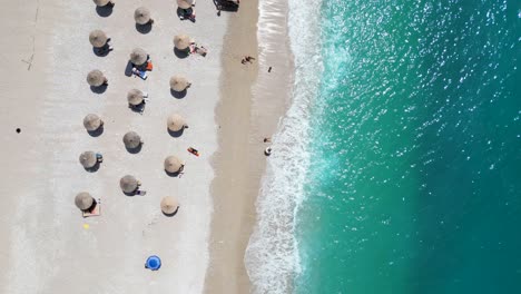 People-relaxing-on-the-beach-and-playing-with-foamy-waves-on-a-summer-day