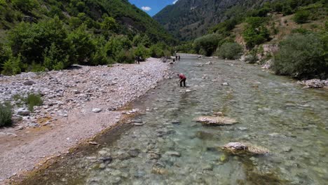 científicos que estudian la vida biológica en el agua del río vjosa que fluye a través de piedras en un hermoso valle en albania