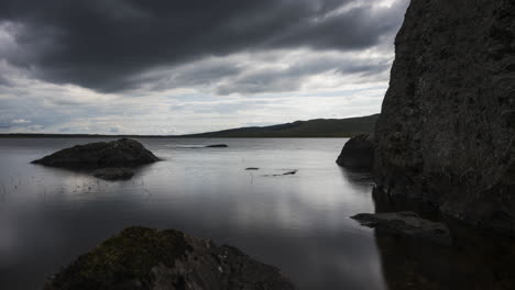 Lapso-De-Tiempo-Del-Lago-Con-Hierba-Y-Grandes-Rocas-En-Primer-Plano-En-Un-Oscuro-Día-De-Verano-Nublado-En-El-Paisaje-Rural-De-Irlanda