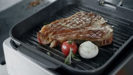 Fresh-steak-frying-at-griddle-pan.-Closeup-beef-with-vegetables-cooking-at-grill