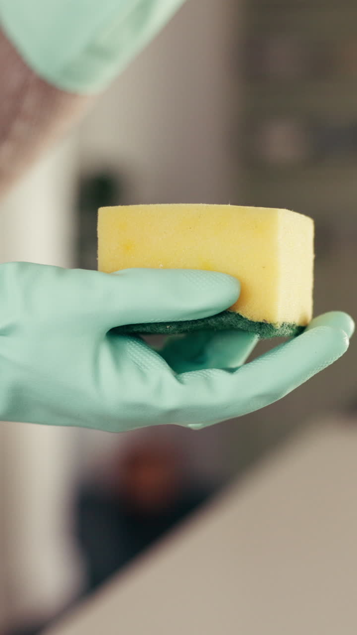 Sponge with dish soap in gloved hand