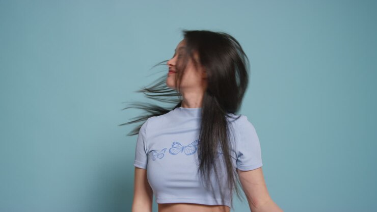 Young Woman In Front Of Blue Studio Background Having Fun Posing For Photo Booth Style Portraits
