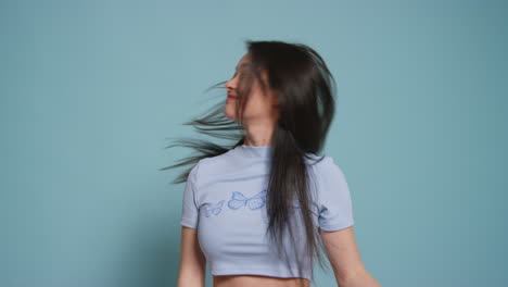 young woman in front of blue studio background having fun posing for photo booth style portraits