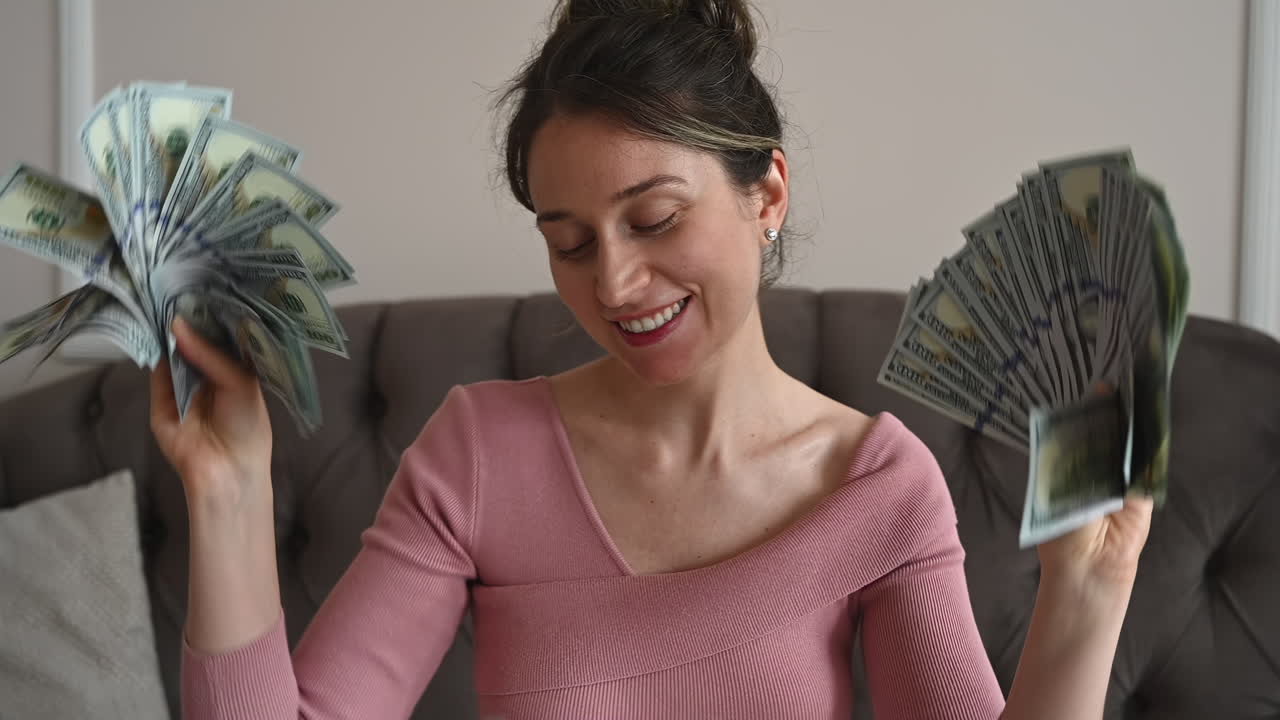 Mujer sonriente admirando grandes fajos de billetes de cien dólares en sus manos