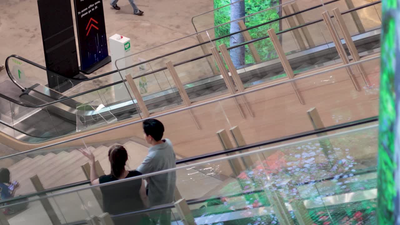 두 사람 이 함께 에스컬레이터 를 타고 내려가고 있다