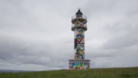 colorful lighthouse with artistic mural in faro de ajo, cantabria, spain