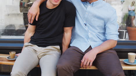 close up of loving male gay couple hugging outside coffee shop