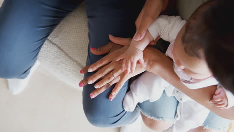 madre con la hija y la nieta bebé de una familia de varias generaciones comparando los tamaños de las manos