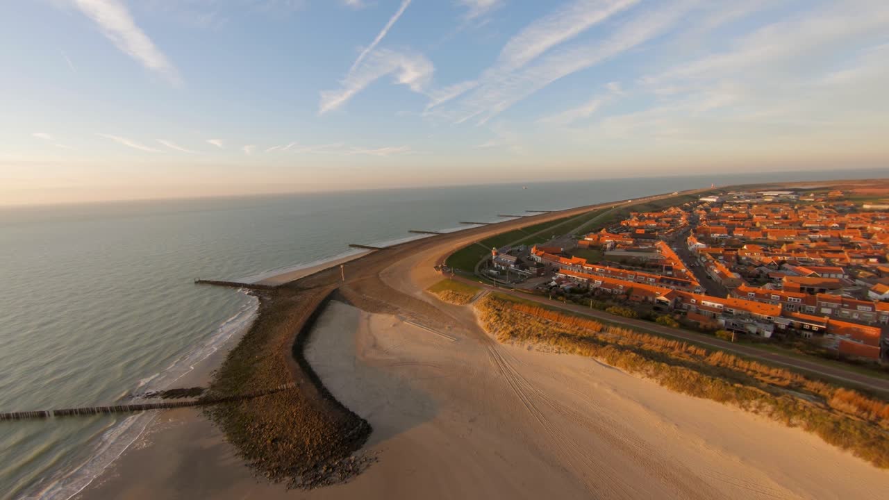 disparo de dron de ángulo bajo a alto de una playa vacía que muestra el pueblo detrás de ella
