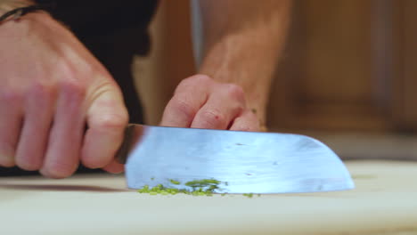 Close-up-hands-with-knife-mincing-chives-on-cutting-board,-slow-motion