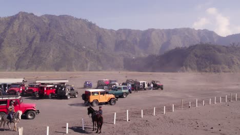 Yellow-jeep-drives-on-sea-of-sand-at-mount-Bromo-east-java,-aerial