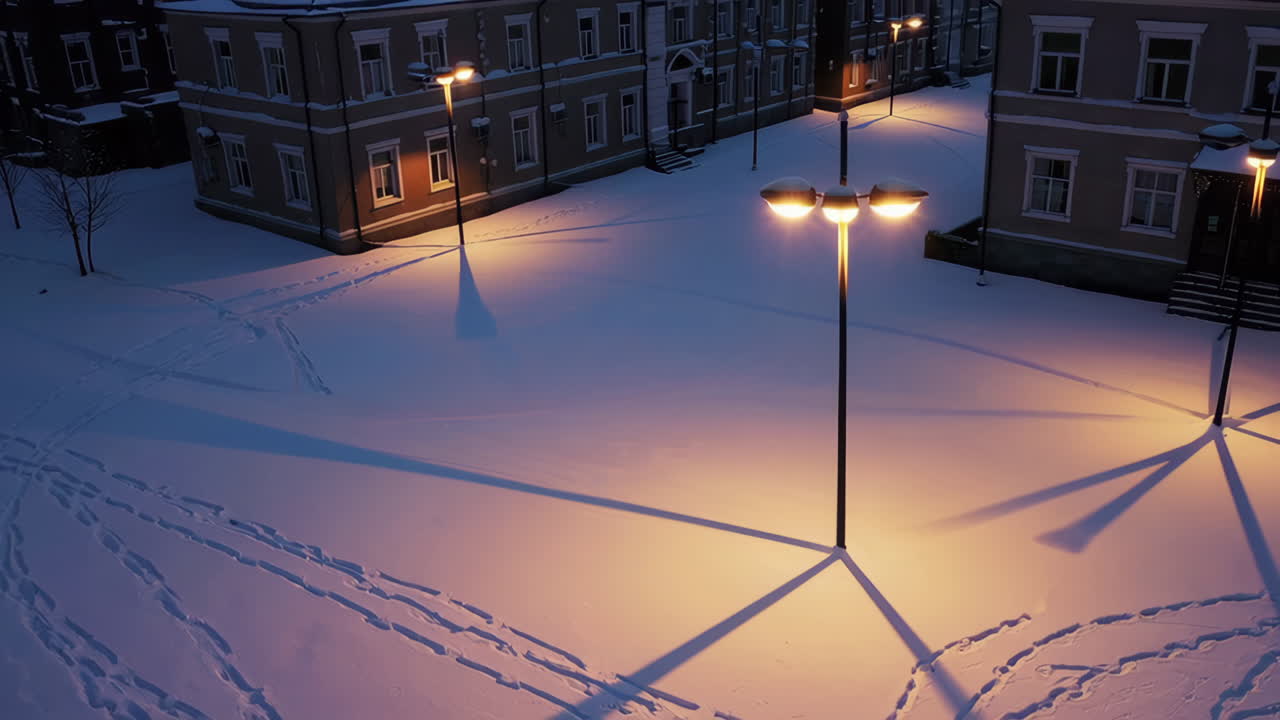 Snow-covered urban square at night with glowing streetlights
