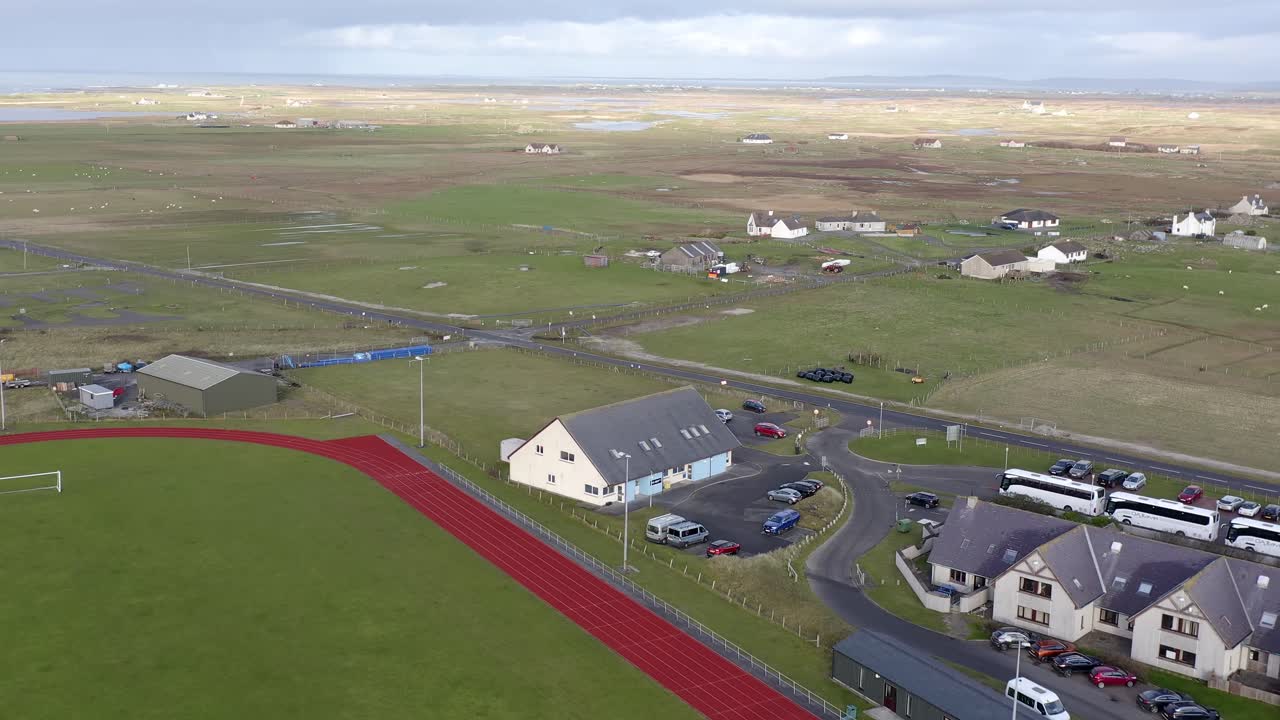 uhi 대학 캠퍼스와 benbecula 섬의 어두운 섬 호텔에서 멀리 떨어진 트랙과 피치 위에서 날아가는 광각 드론  ⁇