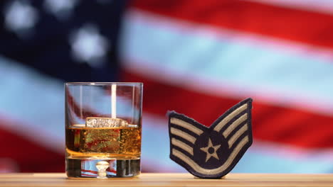 whiskey glass and air force military badge in front of american flag waving