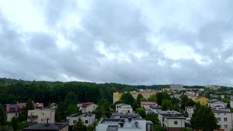 Tiro-De-Lapso-De-Tiempo-De-Nubes-Grises-Volando-Sobre-La-Ciudad-Rural-Con-Casas-Coloridas-Al-Lado-De-Los-árboles-Del-Bosque