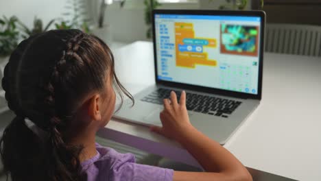 una estudiante hispana aprende en casa a programar un videojuego.