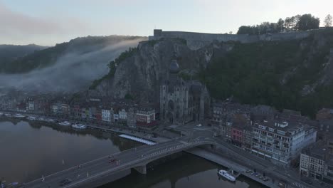 Volando-Hacia-La-Ciudad-De-Dinant-Bélgica-Durante-El-Amanecer-Con-Nubes-Bajas,-Aéreo