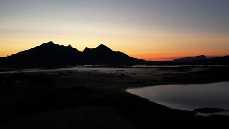 Aerial-shot-of-mountains-revealed-through-fog-during-the-midnight-sun-in-Lofoten,-Norway