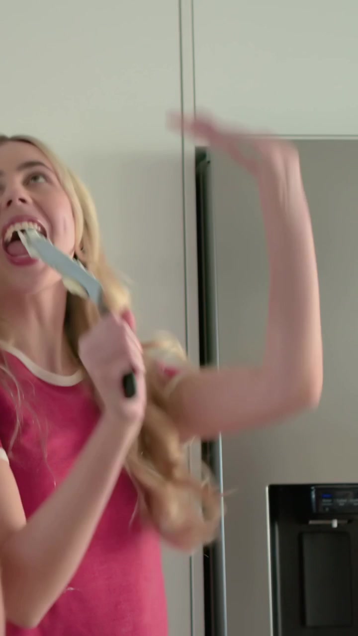 Vertical video: Tasting, two women in yellow overalls and pink finishing cake with knife in kitchen
