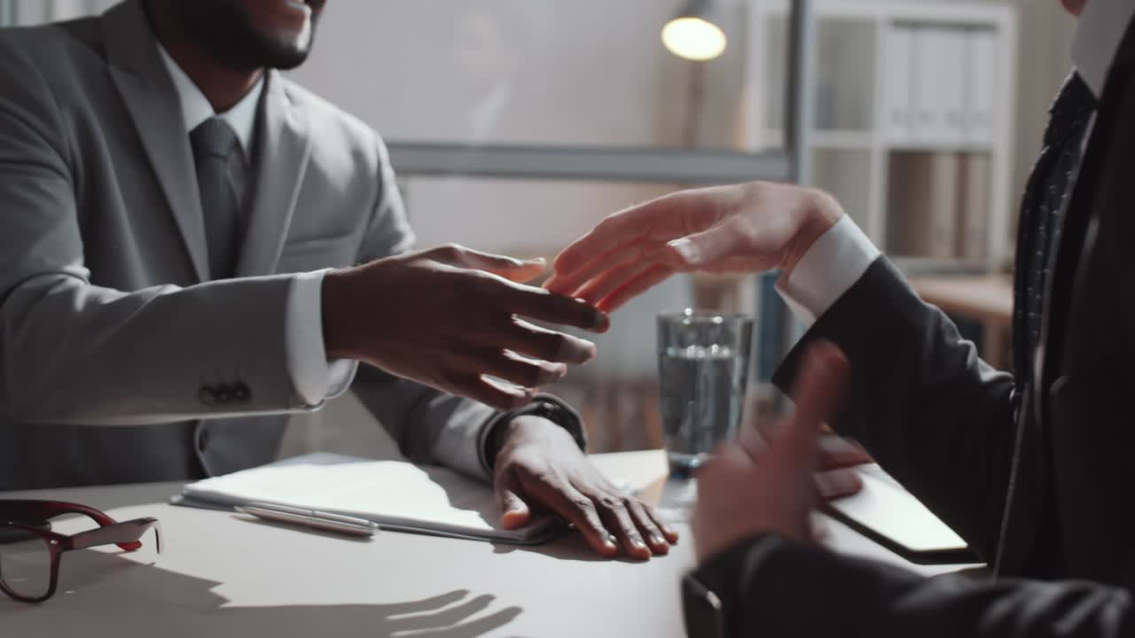 Two Diverse Businessmen Shaking Hands and Having Talk at Desk in Office