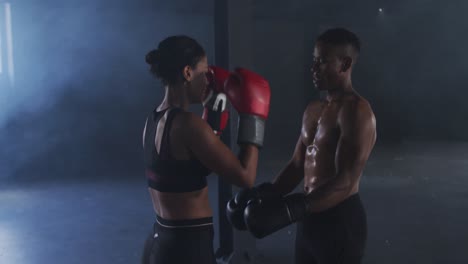 African-american-man-and-woman-wearing-boxing-gloves-training-throwing-punches-in-empty-room