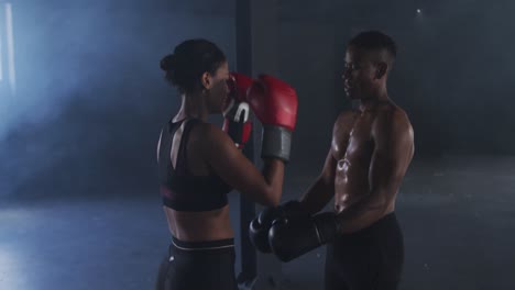 african american man and woman wearing boxing gloves training throwing punches in empty room