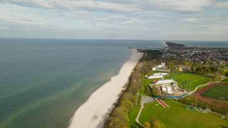 aerial view - drone slowly spinning from wladyslawowo baltic sea beach to the city panorama revealing school, main road and private buildings located in bay area