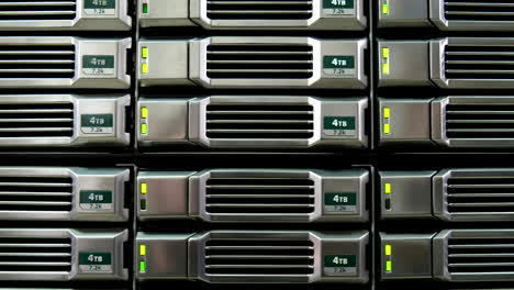 close-up of 4tb hard drives in a server rack, green status lights on