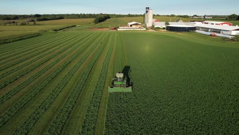 in door county, wi, a farmer on a john deere tractor, cuts his alfalfa field in late august-7