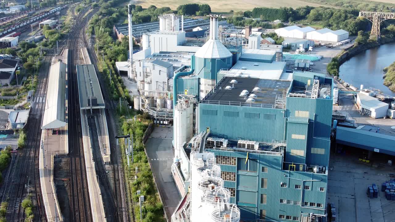 ウォリントン・バンク・キーの鉄道線路に隣接する工業用化学品製造工場を空撮で鳥瞰し、左旋回する映像。
