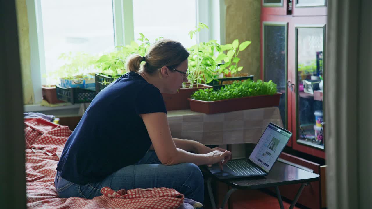 Mujer trabajando desde casa con plantas de interior.