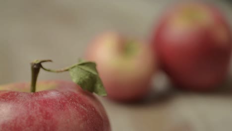 Red apple with stalk close as out of focus hands grab helping of apples from pile