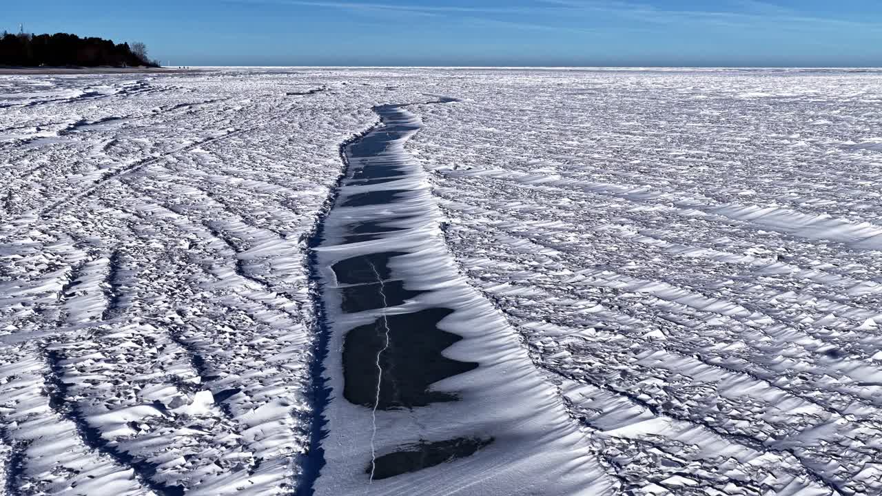 Frozen lake with ice patterns under a clear blue sky on a winter day