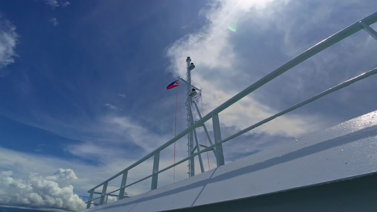 Philippine and Korean flags flying on ferry mast against a clear blue sky, shot from deck.