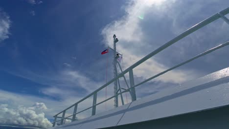 philippine and korean flags flying on ferry mast against a clear blue sky, shot from deck.